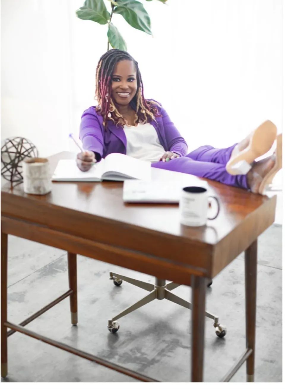 Yvette Howard, LCSW, Private Practice Strategist and founder of Boss Clinician, seated at her desk in a purple suit
